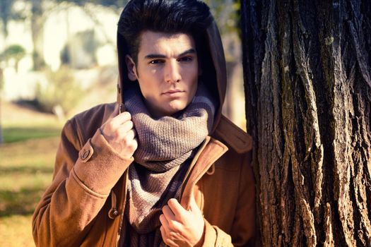 Portrait of a young handsome man, model of fashion, with toupee in a park