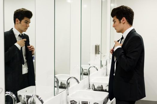 Portrait of a man getting dressed in a public restroom with mirror