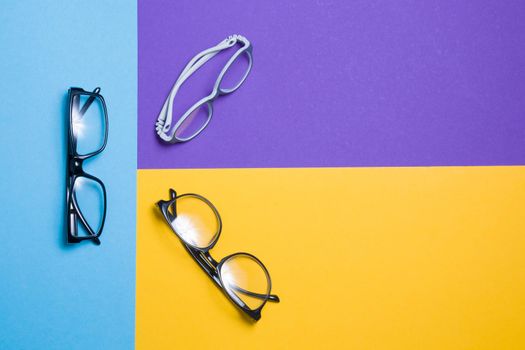 several pairs of glasses lie on a colored background, glasses for adults and children, top view, copy location, top view