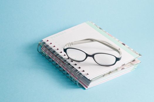 children's glasses lie on a notebook, blue background, copy space, gray bending anti-vandal glasses frame