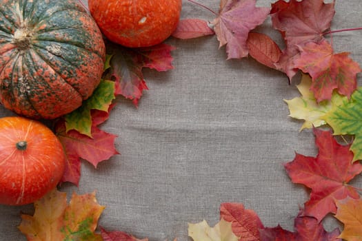 pumpkins and auturm leaves on a linen, fabric texture,copy space, top view