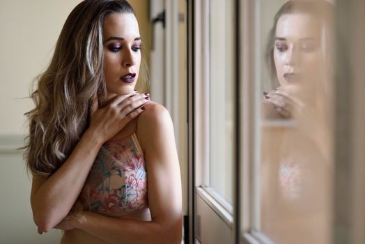 Thoughtful woman looking through the window. Beauty concept.