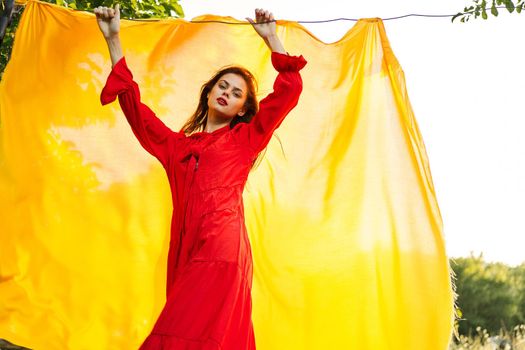 beautiful woman posing in red dress outdoors yellow cloth. High quality photo