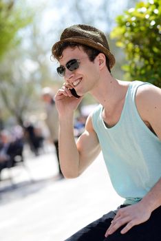 Portrait of an attractive young man wearing hat talking on the mobile phone