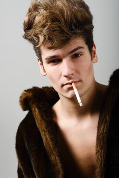 Portrait of a attractive young man wearing fur coat with modern hairstyle