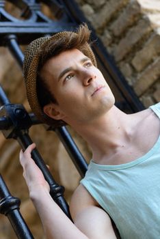 Portrait of a young handsome man, model of fashion, wearing a sun hat in urban background