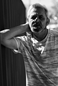 Portrait of mature man, with white hair looking at at camera in urban background. Mature male with grey hair and beard wearing casual clothes.