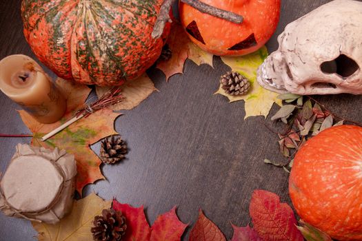 halloween background, scary skull, pumpkins, candle and various autumn objects on a dark brown table, top view. copy space