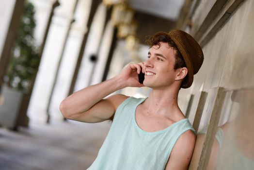 Portrait of an attractive young man wearing hat talking on the mobile phone