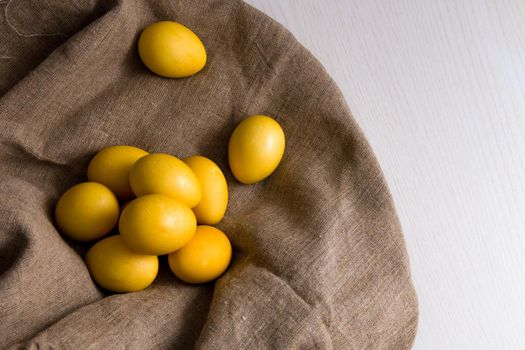 yellow eggs on linen, wooden light background, copy space top view, easter background