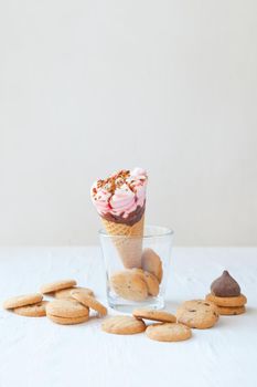 ice cream cone on the glass with cookiesand chocolate. Wafer cone with tasty ice cream and chocolate cookies on table