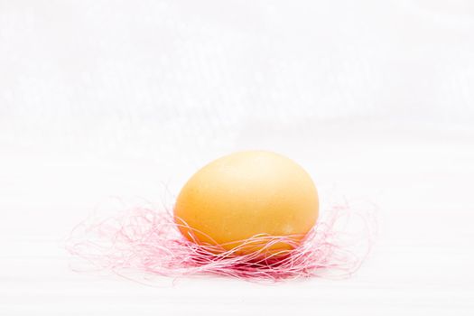 yellow easter egg on pink threads copy space white background