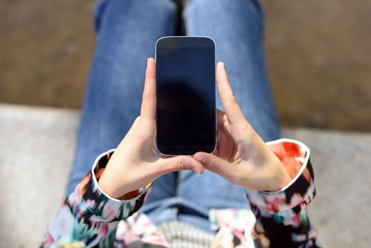 Young woman using a touchscreen smartphone wearing casual clothes