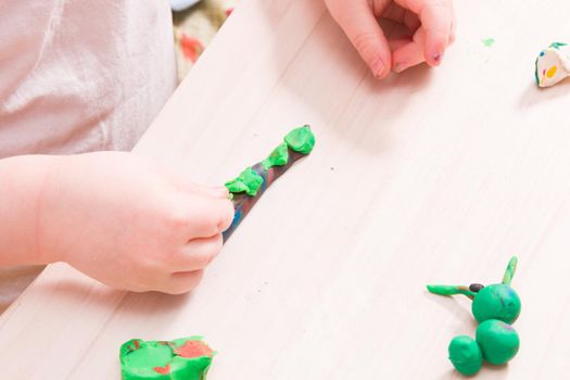 a small child sculpts from plasticine, a wooden light table, classes with a child at home, how to develop fanstasia in a child, games at home for small children