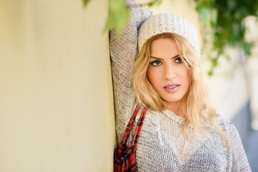 Young woman wearing casual clothes smiling in urban background. Girl wearing sweater and blue jeans