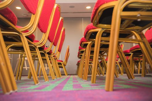 Row of red soft chairs in a conference room with a carpet. The frame goes into perspective. Bottom view