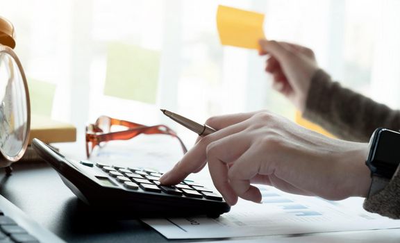 Close up accountant working on desk using calculator for calculate finance report in office.