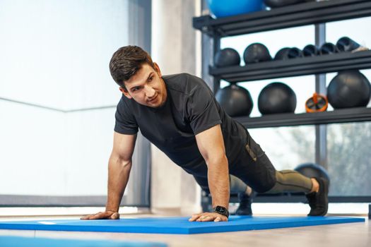 Young athletic man doing push-ups in a gym, close up photo