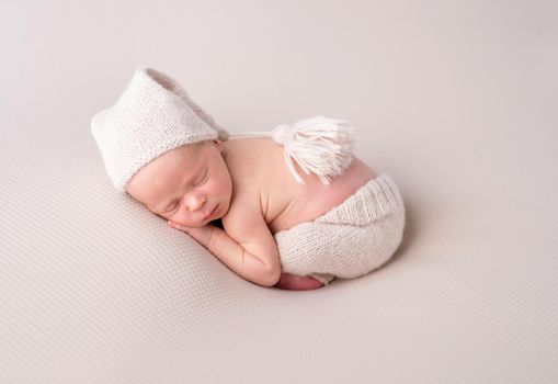 Cute baby in white knitted hat and pants sweetly sleeping