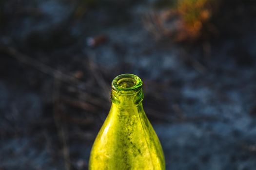 green dirty glass bottle close-up on a sunny day in nature.