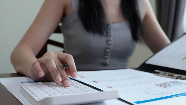 Close up woman using calculator and laptop for calaulating finance, tax, accounting, statistics and analytic research concept.