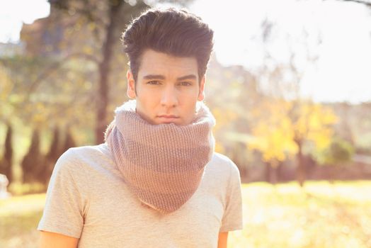 Portrait of a young handsome man, model of fashion, with modern hairstyle in the park