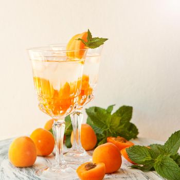 Summer drink- apricot cocktail with ice in glasses. Refreshing summer homemade alcoholic or non-alcoholic cocktails or Detox infused flavored water