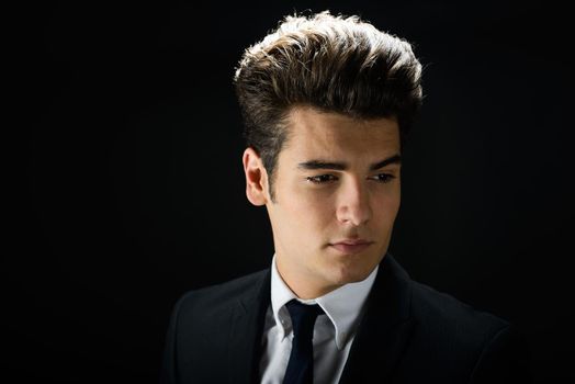 Portrait of a young businessman, on black background