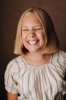 A happy child, a little girl in a gray T-shirt on a beige background.