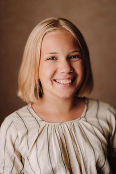 A happy child, a little girl in a gray T-shirt on a beige background.