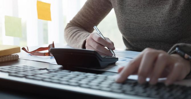 woman working with calculator for financial document in office. male accountant doing accounting and calculating. bookkeeper making calculation. Savings, finance.