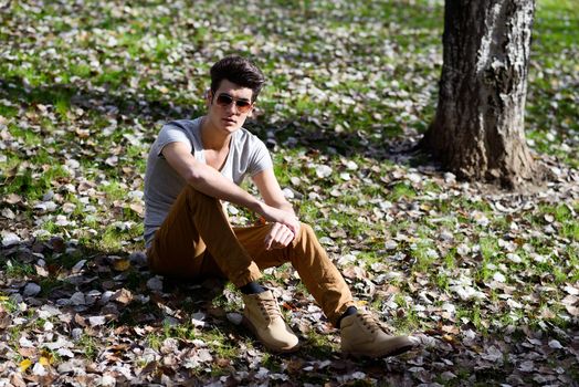 Portrait of a young handsome man, model of fashion, with modern hairstyle in the park