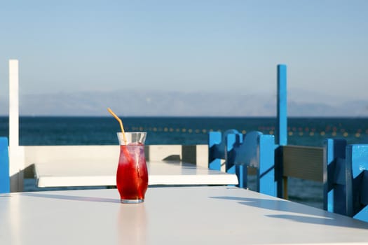 cherry drink standing near sea in greece restauraunt. glass of fresh red juice on table in Korfu