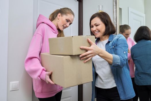 Delivery of goods, social services, post, home, lifestyle, online shopping. Two women with cardboard boxes near the front door of the house