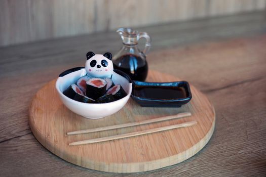 plate of sushi rolls made for children on wooden table with chopsticks and soya. healthy korean food with salmon for kids