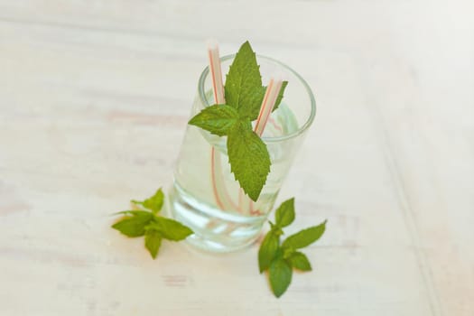 Summer healthy homemade citrus lemonade infused water drink, mint leaves in glass on grey background. Close up mojito coctail. Selective focus. Copy space