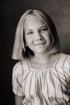 A happy child, a little girl in a gray T-shirt on a beige background. black and white photo.