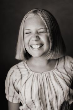 A happy child, a little girl in a gray T-shirt on a beige background. black and white photo.