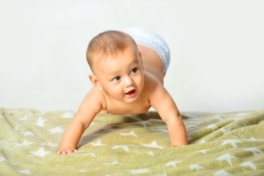 Newborn child relaxing in bed. Happy baby playing. Beautiful expressive adorable happy cute laughing smiling infant. Copy space. Little baby crawling on the bed
