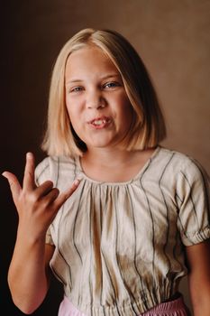 A happy child, a little girl in a gray T-shirt on a beige background.