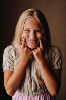 A happy child, a little girl in a gray T-shirt on a beige background.