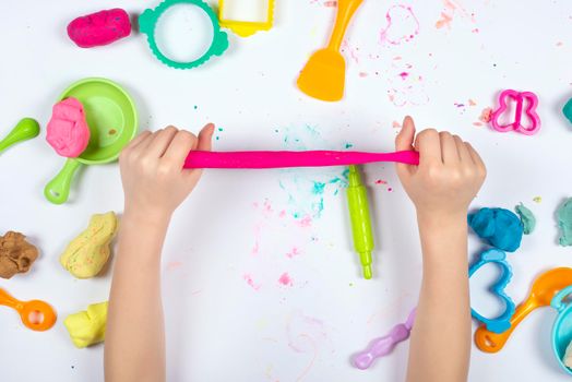 Little girl play with modeling clay on white background. Top view. Home Education game with clay. Early development concept