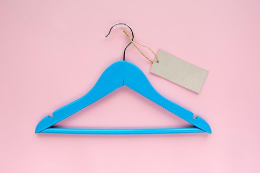 Wooden blue hanger with black paper label isolated on pink paper background. Clothing tag, label blank mockup template, to place your design. Black friday final sale banner.