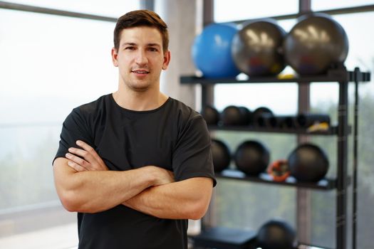 Portrait of a young handsome fitness trainer in a gym, close up