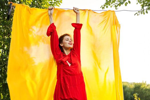 beautiful woman posing in red dress outdoors yellow cloth. High quality photo