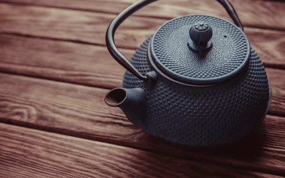Old vintage iron teapot on a wooden background, top view.