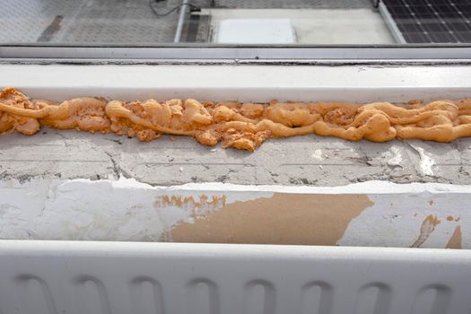 Worker using a polyurethane foam for installation of window sill. Installing window sill restoration,renovation house,building close-up