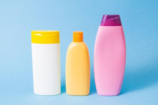 three different plastic bottles without labels for shampoo and shower gels on a blue background