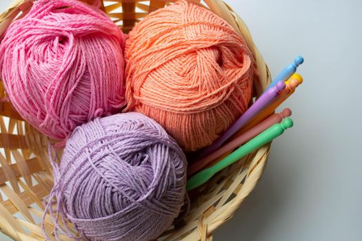Balls of colored yarn in a basket on white background.