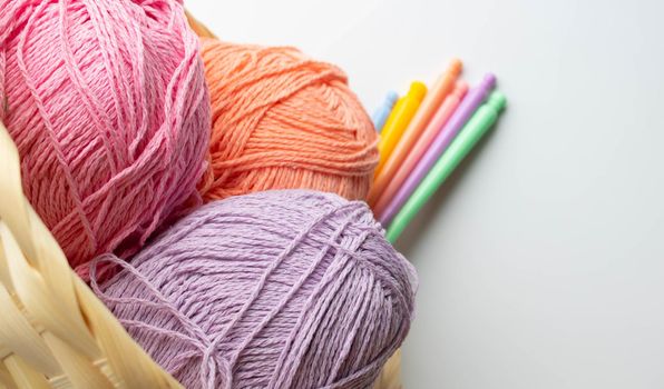 Balls of colored yarn in a basket on white background.